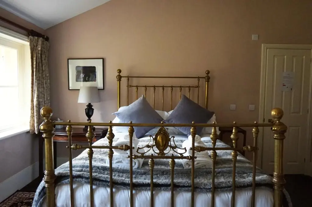A brass bed with a wool throw in one of our rooms